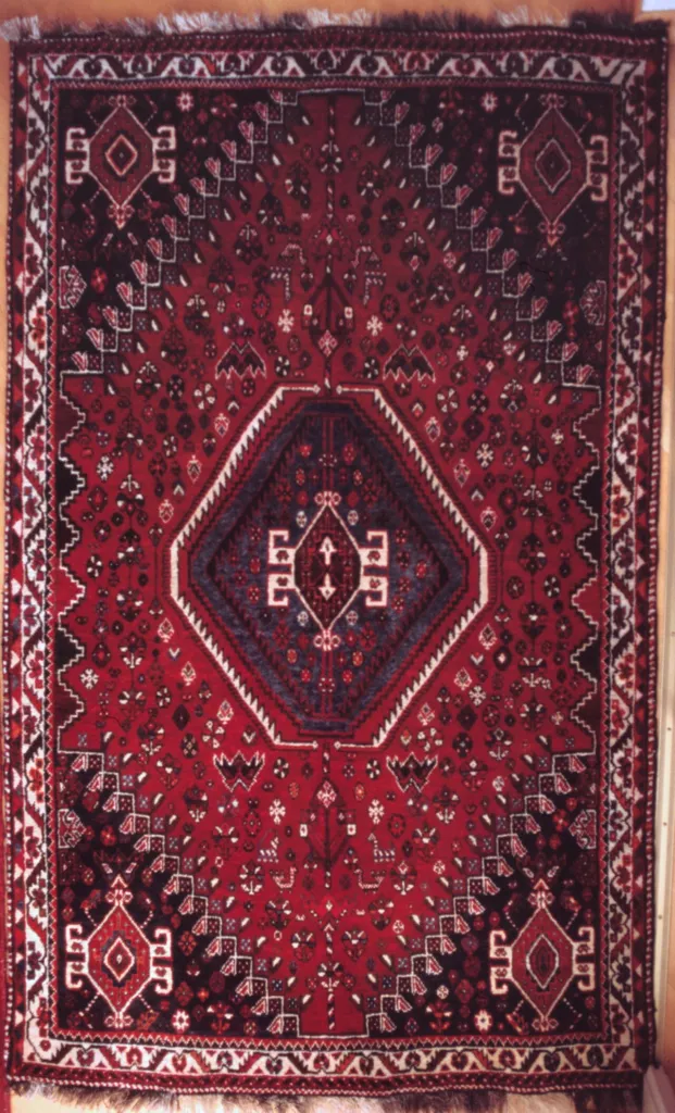 A wool rug woven by the Qashqai people of Iran. Harmal seed is one of the historical red-to-yellow wool dyes of this region (see the dye note above); the dyes in this particular rug are not documented.