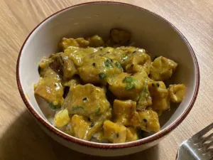 Bowl of yellow tofu curry coloured with Curcuma longa, served with rice