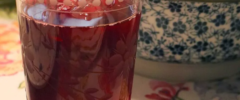 Glass of deep red Hibiscus sabdariffa tea on a table