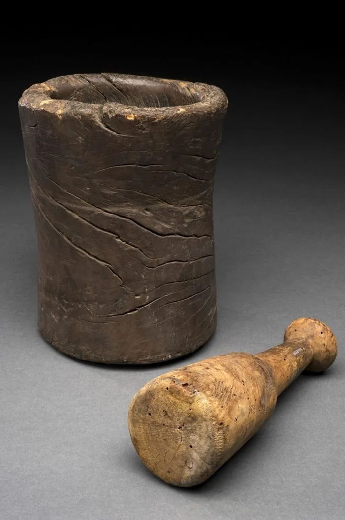 An old turned wooden mortar and pestle from Europe, photographed against a plain background